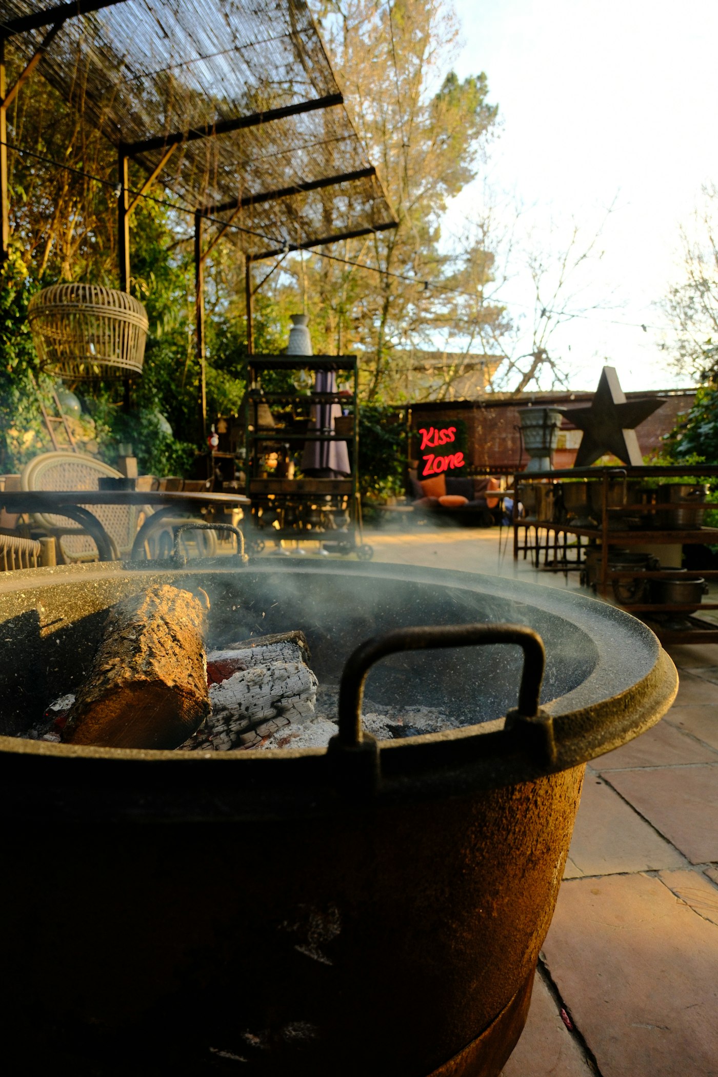 Fire pit at dusk with burning logs and smoke